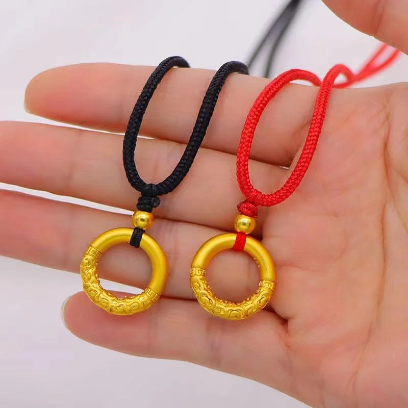 Gilded Circle Amulet — Gold-tone pierced circle amulet pendant on a woven cord, held in the hand
